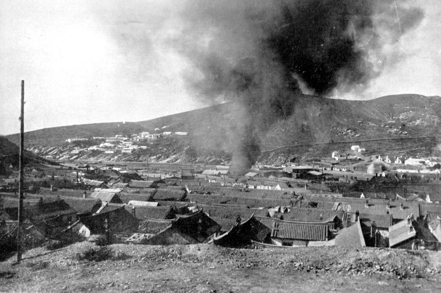 Smoke from residences following the bombardment of Port Arthur by the Japanese Third Army, August 1904. After the Japanese took Port Arthur in 1894 during the First Sino-Japanese War, they slaughtered innocent civilians in Port Arthur; now, a decade later, the people were once again victims of Japanese bombardment. As for the Russians, after they got a lease on Port Arthur and Dalian in 1898, they built strong fortifications in Lüshun and over 20 concrete permanent batteries along 50 li around Lüshunkou, for which they mobilised about 60,000 Chinese workers each day. There were about 4,200 Russian troops in Port Arthur, with about 11,000 naval troops from its Pacific fleet subsequently deployed there, along with 646 cannons and 62 machine guns. The Japanese Third Army - including the First and Tenth divisions and three artillery regiments, along with the Ninth division and a special squad - numbered about 57,000. On 7 August, the Japanese began bombarding the town area and the Russian fleet in Port Arthur.