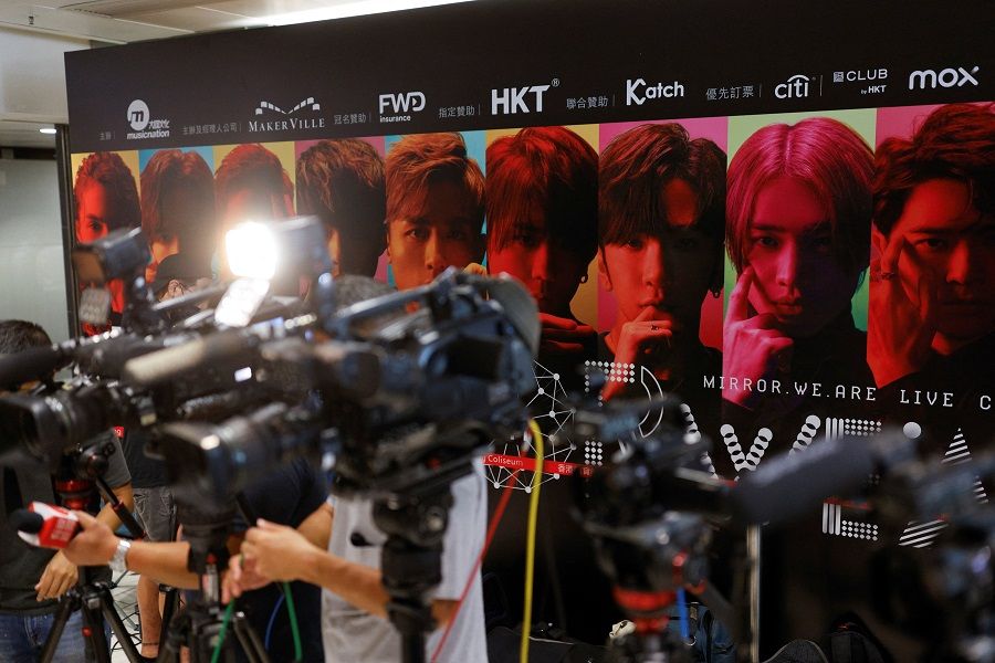 Members of the media stand in front of a background showing Hong Kong boy band Mirror during a news conference after a giant video panel fell onto the stage during a concert, in Hong Kong, China, 29 July 2022. (Tyrone Siu/Reuters)
