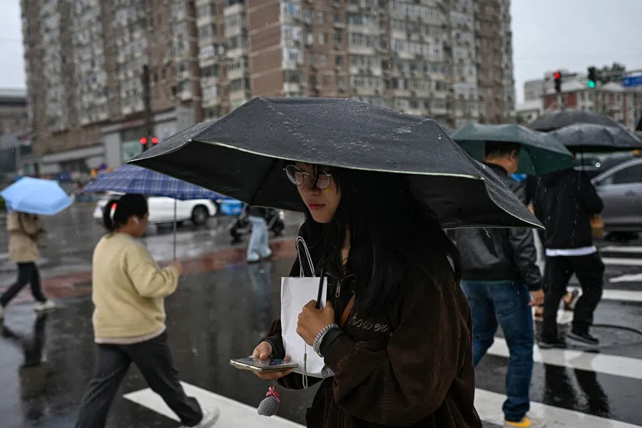 Pedestrians holding umbrellas cross a street on a rainy day in Beijing on 9 October 2025. (Wang Zhao/AFP)