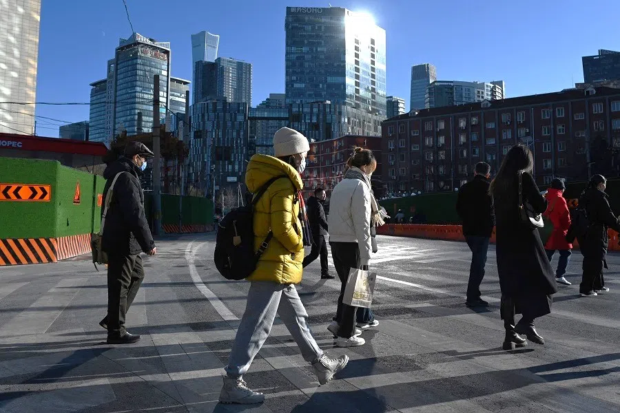 People cross a road in Beijing, China, on 8 December 2024. (Greg Baker/AFP)