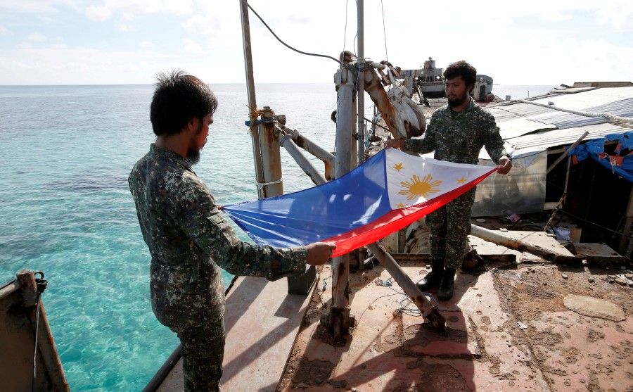 Philippine Marines fold a Philippine national flag during a flag retreat at the BRP Sierra Madre, a marooned transport ship in the disputed Second Thomas Shoal, part of the Spratly Islands in the South China Sea, 29 March 2014. (Erik De Castro/Reuters)