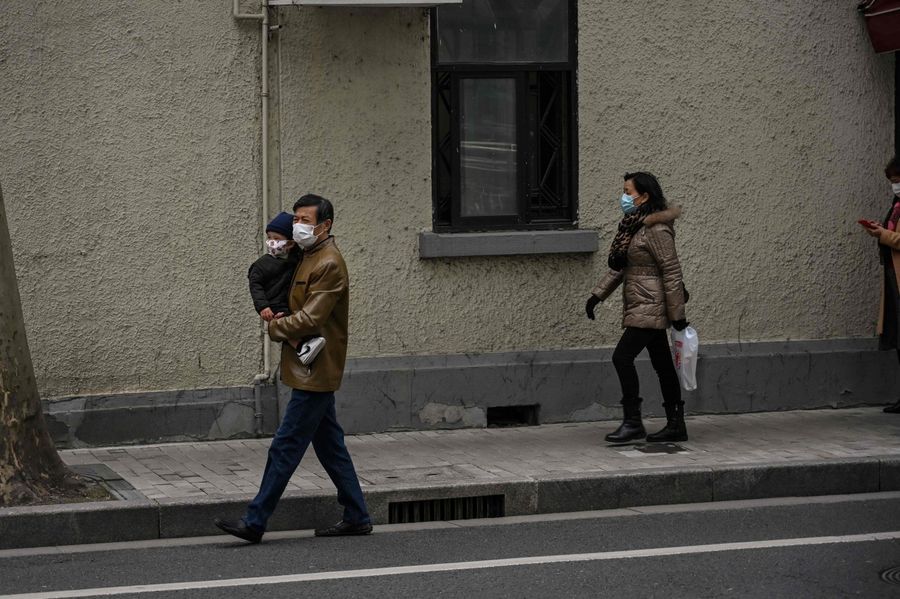 People wearing face masks walk on a street in Shanghai on 3 March 2020. (Hector Retamal/AFP)