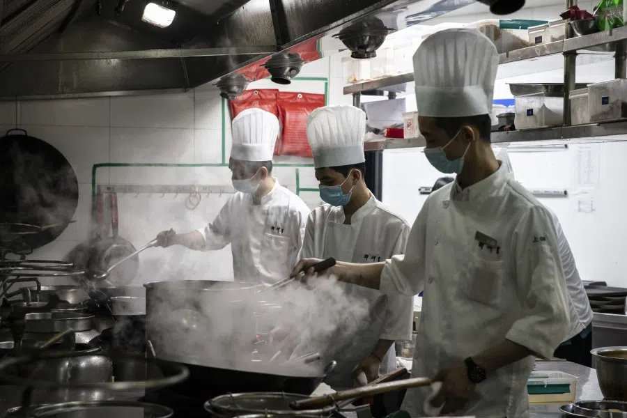 Cooks wear protective face masks as they prepare food for customers in the kitchen at a Zuihuihuang restaurant in Shanghai, China, on 12 February 2021. (Qilai Shen/Bloomberg)