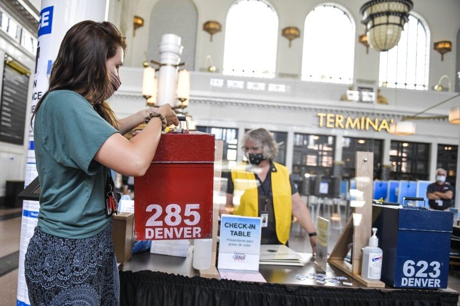An elections judge collects a ballot box from the Union Station polling center as people vote in the primary election, 30 June 2020 in Denver, Colorado. (Michael Ciaglo/AFP)