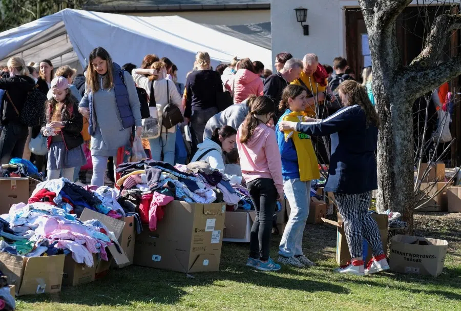 Refugees from Ukraine queue for food and clothing outside a tent at a donation collection point organised by Dresden's Ukrainian Catholic parish, amid Russia's invasion of Ukraine, in Dresden, Germany, 27 March 2022. (Matthias Rietschel/Reuters)
