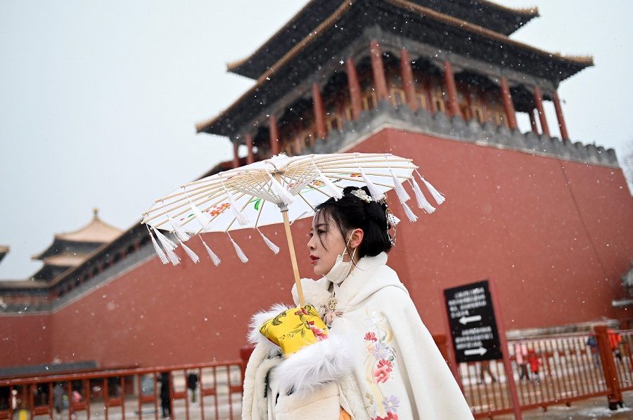 A woman wearing a traditional outfit known as a hanfu visits the Forbidden City on a snowy day in Beijing, China, on 20 January 2022. (Wang Zhao/AFP)
