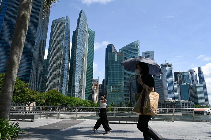 People walk along the Marina Bay promenade next to the financial business district in Singapore on 9 May 2022. (Roslan Rahman/AFP)