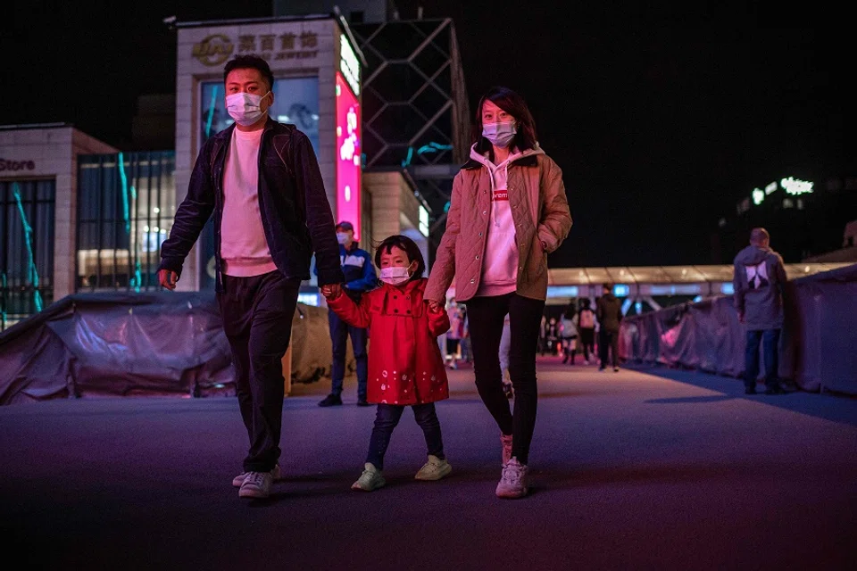 A family wearing face masks walks outside a shopping mall in Beijing on 11 October 2020. (Nicolas Asfouri/AFP)