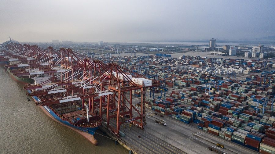 Ships are docked next to stacked containers and gantry cranes at the Port of Nansha, operated by Guangzhou Port Group Co., in the Nansha district of Guangzhou, China, on 20 November 2020. (Qilai Shen/Bloomberg)