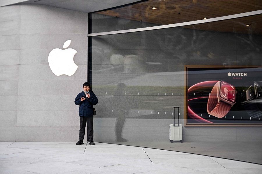 A man stands outside a recently opened Apple Store in Shanghai's Jing'an district on 26 March 2024. (Hector Retamal/AFP)