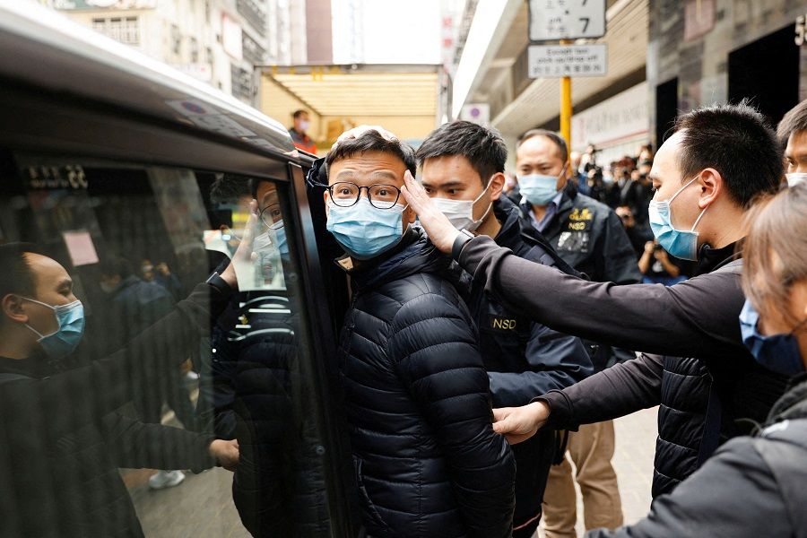Stand News acting chief editor Patrick Lam, one of the two journalists from the outlet arrested and charged with sedition, is escorted by police as they leave after a search of his office in Hong Kong, China, 29 December 2021. (Tyrone Siu/File Photo/Reuters)