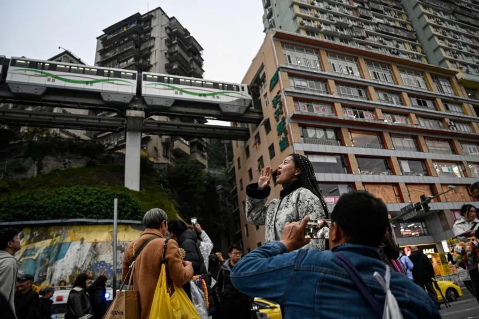 A woman poses for photos as a train arrives at the Liziba metro station at the Liziba sightseeing platform in southwestern China’s Chongqing municipality on 15 December 2025. (Jade Gao/AFP)