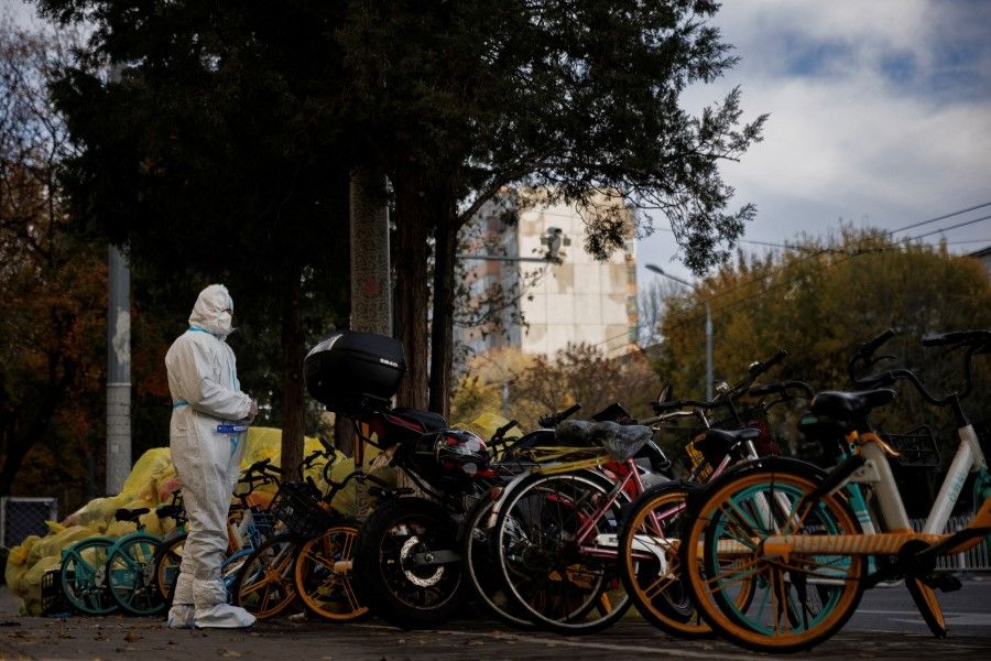 A pandemic prevention worker in a protective suit stands outside an apartment compound that was placed under lockdown as outbreaks of the coronavirus disease (Covid-19) continue in Beijing, China, 12 November 2022. (Thomas Peter/Reuters)