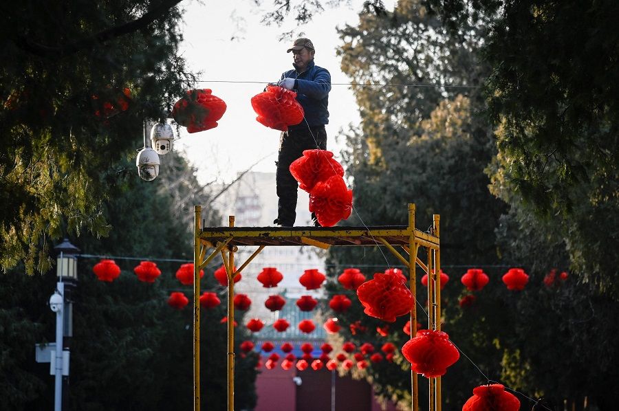A worker hangs red lanterns at a park ahead of Lunar New Year celebrations at a park in Beijing, China, on 11 January 2022. (Wang Zhao/AFP)