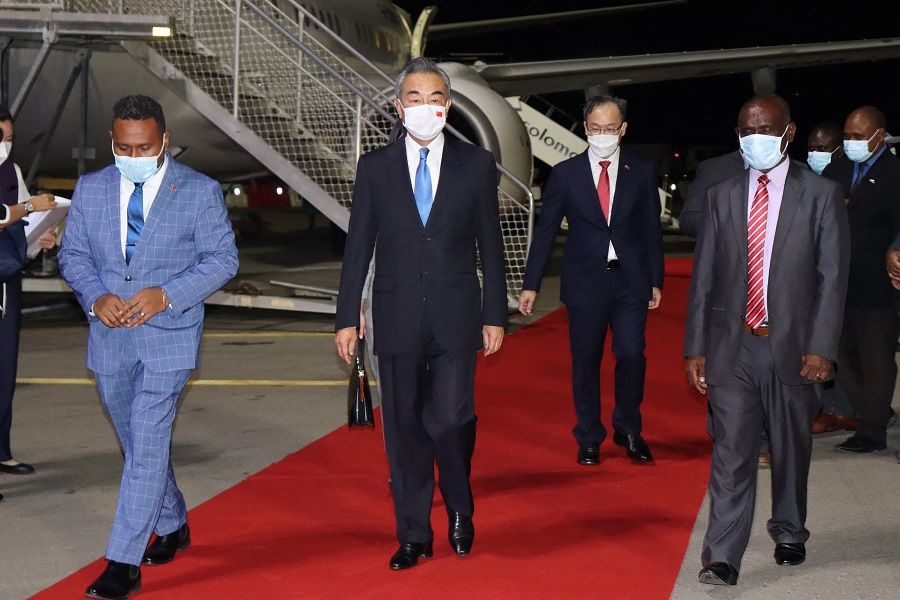This picture taken on 25 May 2022 shows Solomon Island's Foreign Minister Jeremiah Manele (left) and Chief Protocole Walter Diamana (right) escorting Chinese Foreign Minister Wang Yi (centre) upon his arrival at the Henderson International Airport in Honiara, Solomon Islands. (Stringer/AFP)