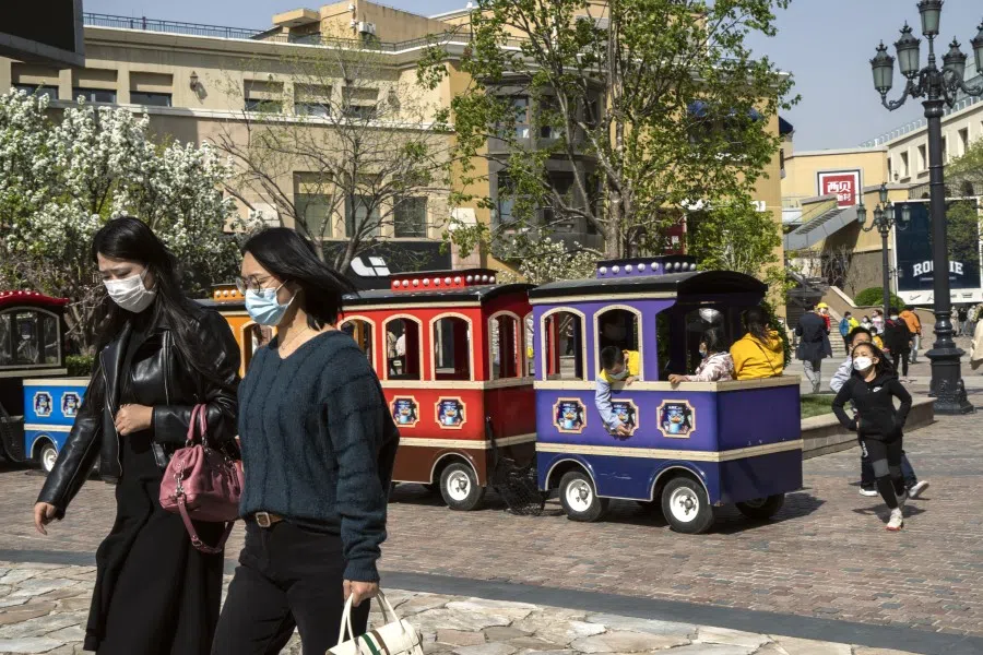 Pedestrians walk past children sitting in an amusement train ride in Beijing, April 4, 2020. China reported no new coronavirus deaths for the first time since the pandemic emerged, adding to signs that the crisis may be easing in some areas. (Giulia Marchi/Bloomberg)