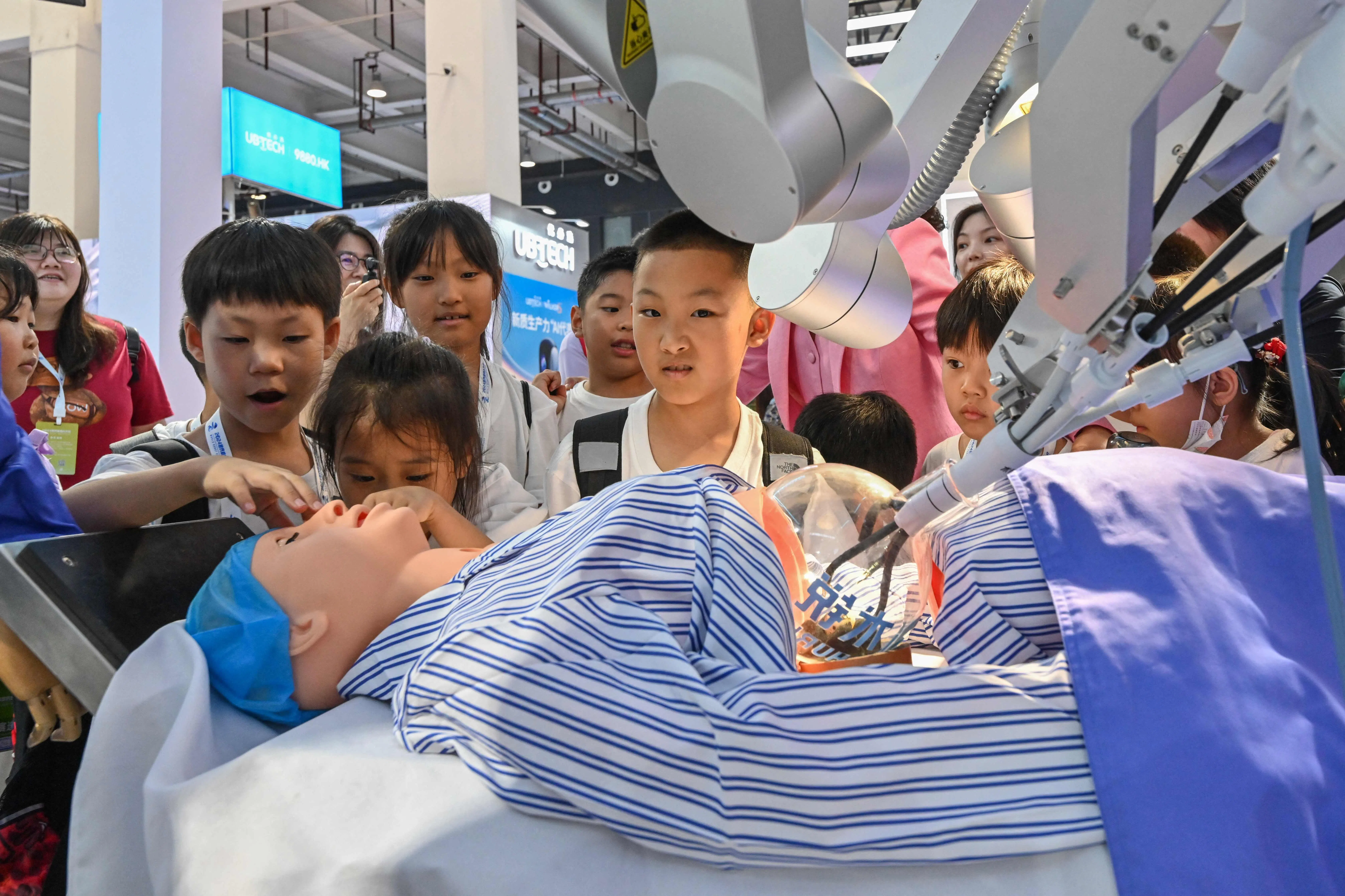 School children check a robot used during surgery at the World Robot Conference in Beijing on 21 August 2024. (Adek Berry/AFP)