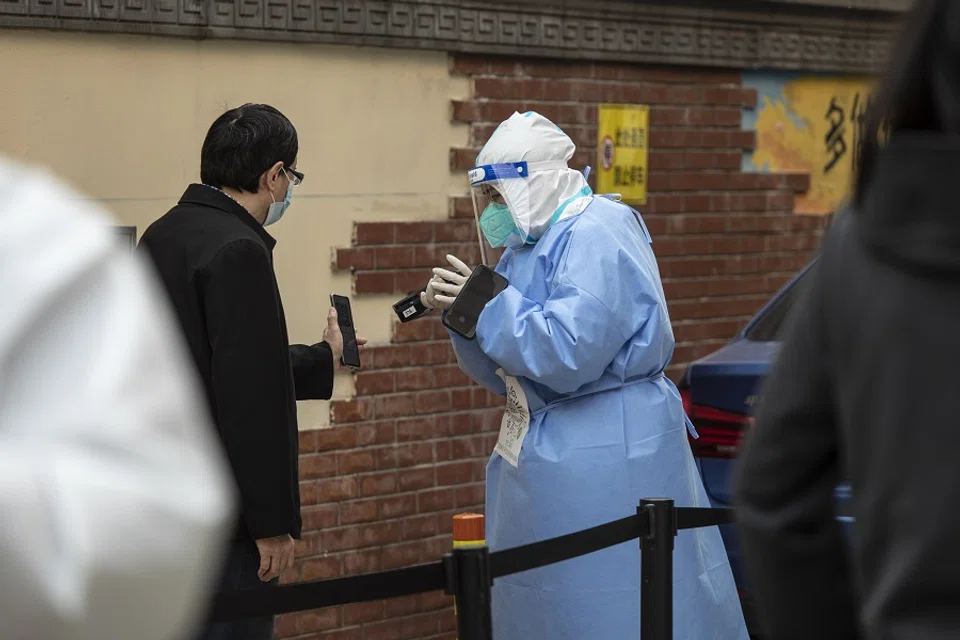 A worker in personal protective equipment facilitates a round of Covid-19 testing during a lockdown in Shanghai, China, on 7 April 2022. (Qilai Shen/Bloomberg)