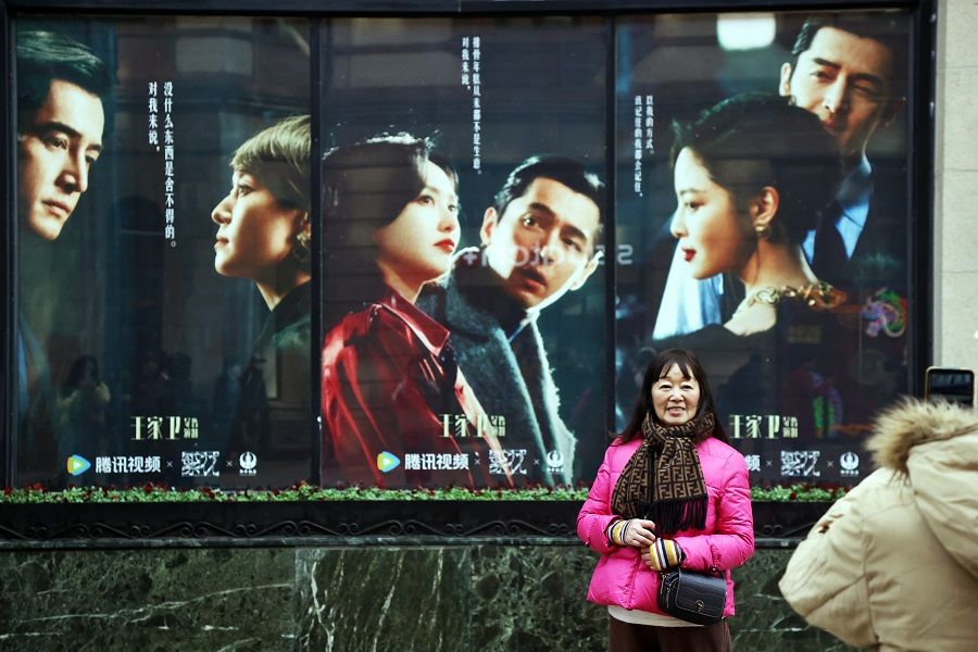 A woman poses for photographs in front of publicity posters for Blossoms Shanghai in front of Fairmont Peace Hotel in Shanghai, China, on 11 January 2024. (CNS)