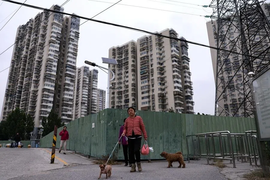 A resident walks a dog near a residential compound in Beijing, China, on 16 October 2025.