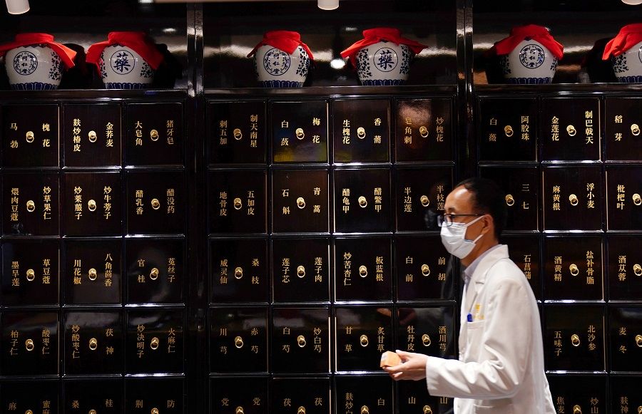 A staff member wearing a face mask following the Covid-19 outbreak walks past cabinets for herbs at Zhima Health store, a cafe and healthcare retail shop owned by the traditional Chinese medicine (TCM) brand Tongrentang, in Beijing, China, on 29 July 2020. (Tingshu Wang/Reuters)