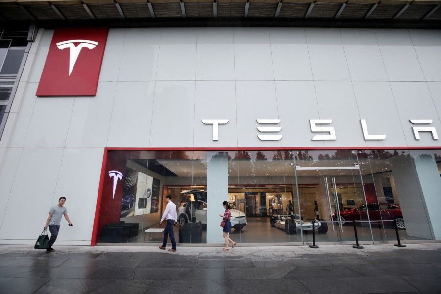 People walk past a showroom outside Tesla China headquarters at China Central Mall in Beijing, China, 11 July 2018. (Jason Lee/File Photo/Reuters)