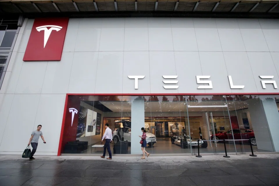 People walk past a showroom outside Tesla China headquarters at China Central Mall in Beijing, China, 11 July 2018. (Jason Lee/File Photo/Reuters)