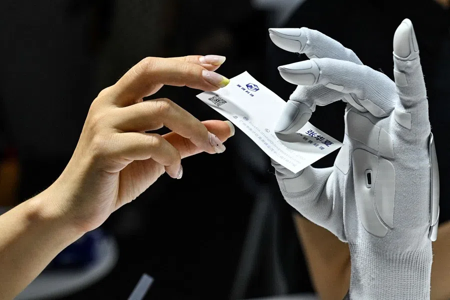 A woman gives a card to a hybrid-driver hand by Xynova Technology during the World Artificial Intelligence Conference (WAIC) in Shanghai on 18 July 2026.