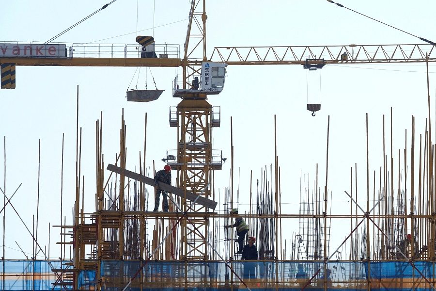 A Vanke sign is seen above workers working at the construction site of a residential building in Dalian, Liaoning province, China, 16 September 2019. (Stringer/Reuters)