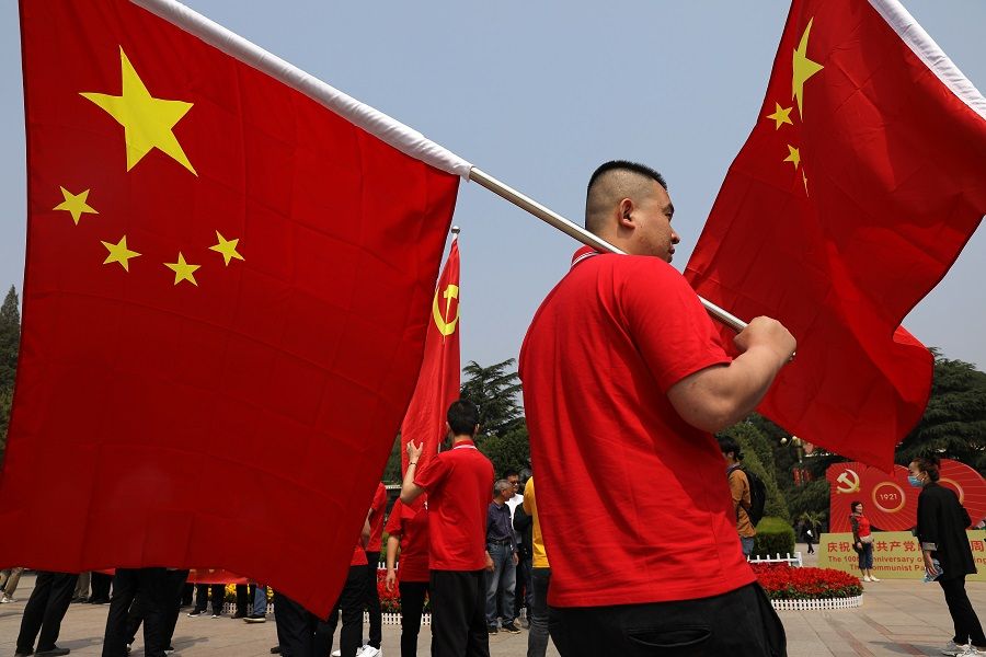 A visitor carries a Chinese national flag at Xibaipo Memorial Hall, ahead of the 100th founding anniversary of the Communist Party of China in Xibaipo, Hebei province, China, 12 May 2021. (Tingshu Wang/Reuters)