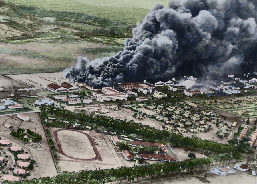 In December 1941, Japanese planes bombed Pearl Harbor and the airfield in Hawaii. This photo was shot from a Japanese plane, showing billows of smoke rising from the burning airfield, with neat rows of fighter planes on the ground.