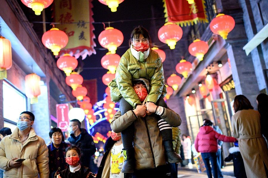 People wearing face masks walk at Qianmen street in Beijing, China, on 11 February 2021. (Noel Celis/AFP)