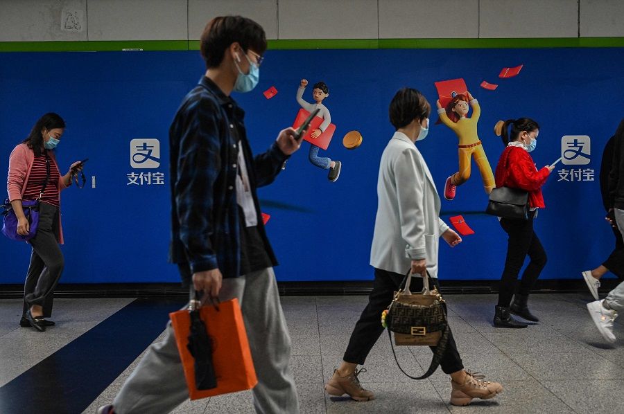 People walk past an advertisement for Alipay in a subway station in Shanghai, China, on 12 October 2021. (Hector Retamal/AFP)