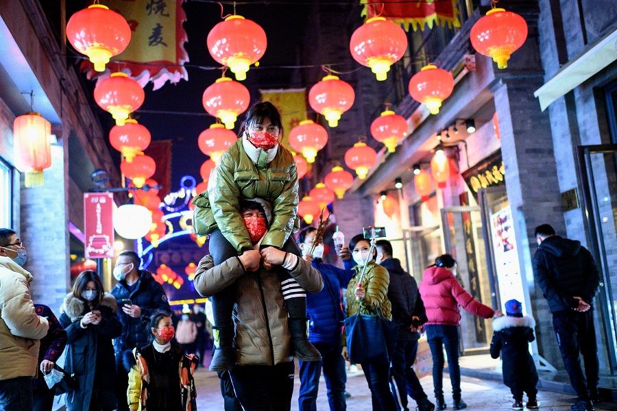 People wearing face masks walk at Qianmen street in Beijing, China, on 11 February 2021. (Noel Celis/AFP)