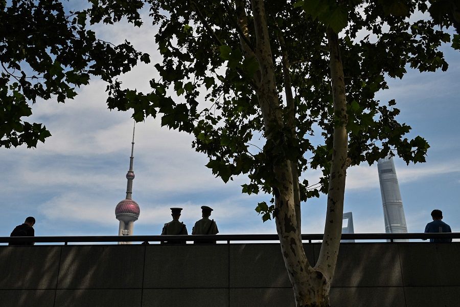 Chinese paramilitary policemen (centre) keep watch at the promenade on the Bund along the Huangpu River, as the Oriental Pearl Radio and Television Tower (left) is seen in Shanghai, China, on 24 September 2021. (Hector Retamal/AFP)
