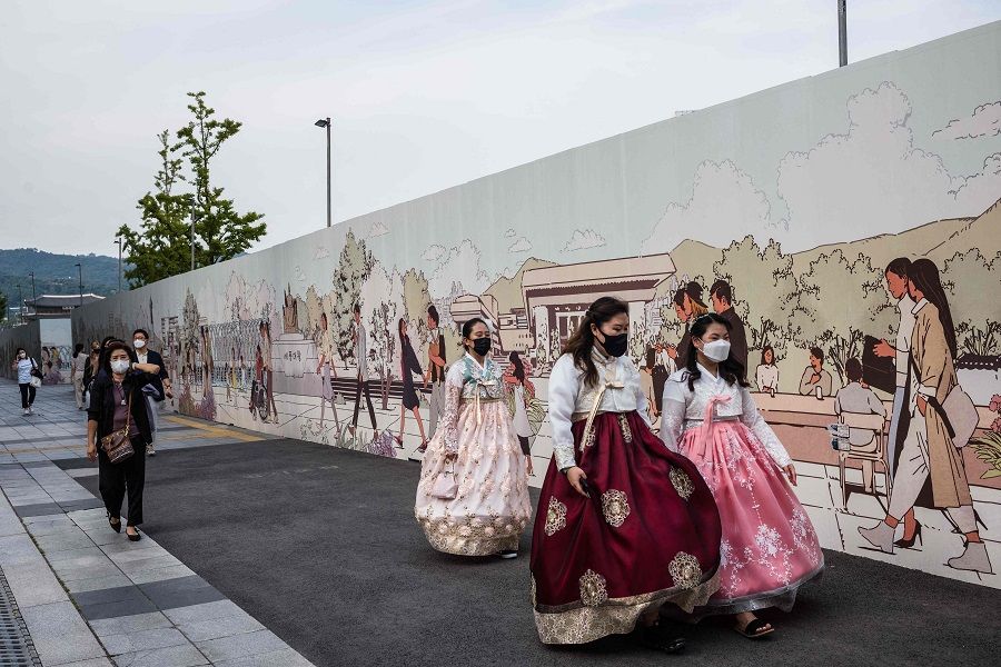 Three women wearing traditional hanbok dresses walk on a pavement in Seoul, South Korea, on 9 September 2021. (Anthony Wallace/AFP)