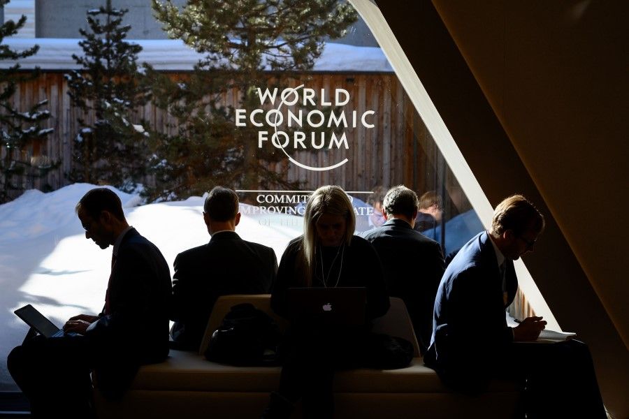 In this file photo taken on 23 January 2020, participants check their messages on electronic devices during the World Economic Forum (WEF) annual meeting in Davos. (Fabrice Coffrini/AFP)