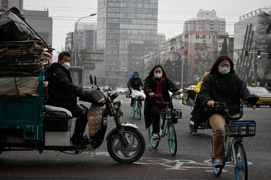 People ride bicycles on a street while it snows in Beijing, China, on 9 February 2023. (Jade Gao/AFP)