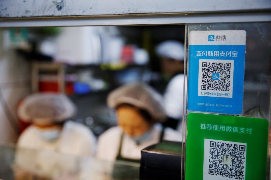 A QR code of digital payment device Alipay by Ant Group, an affiliate of Alibaba Group Holding, is seen next to a QR code of WeChat Pay at a food stall inside a market, in Beijing, China, 2 November 2020. (Tingshu Wang/Reuters)