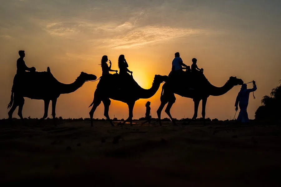 Tourists ride camels at a desert resort in Dubai at sunset on 19 October 2025.