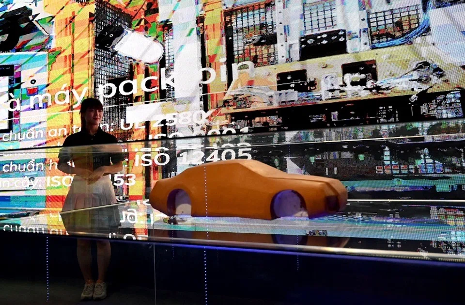 A woman stands next to a display at the launch ceremony for VinFast electric car models in Hanoi, Vietnam, on 7 July 2023. (Nhac Nguyen/AFP)