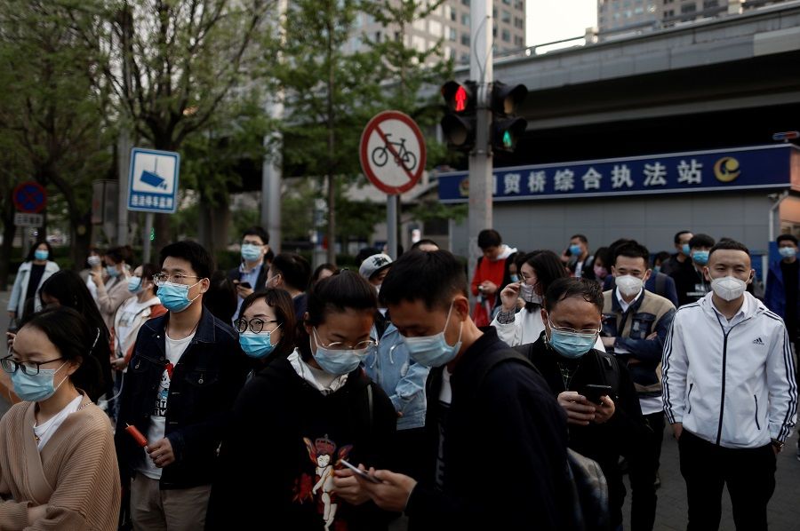 People wearing protective face masks leave work after office hours in Beijing's central business district on 17 April 2020. (Thomas Peter/Reuters)