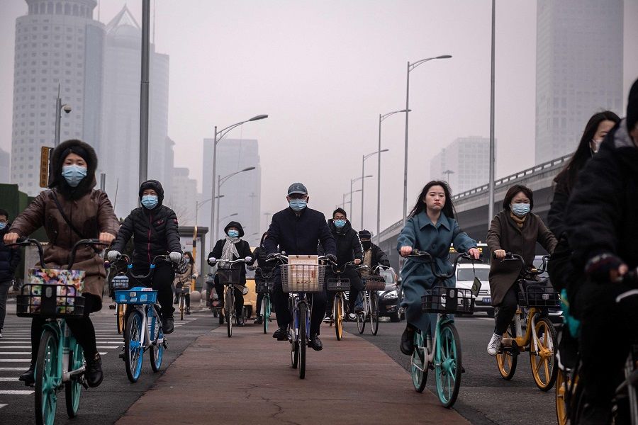 People commute during the morning rush hour in the financial district in Beijing, China, 4 March 2021. (Nicolas Asfouri/AFP)