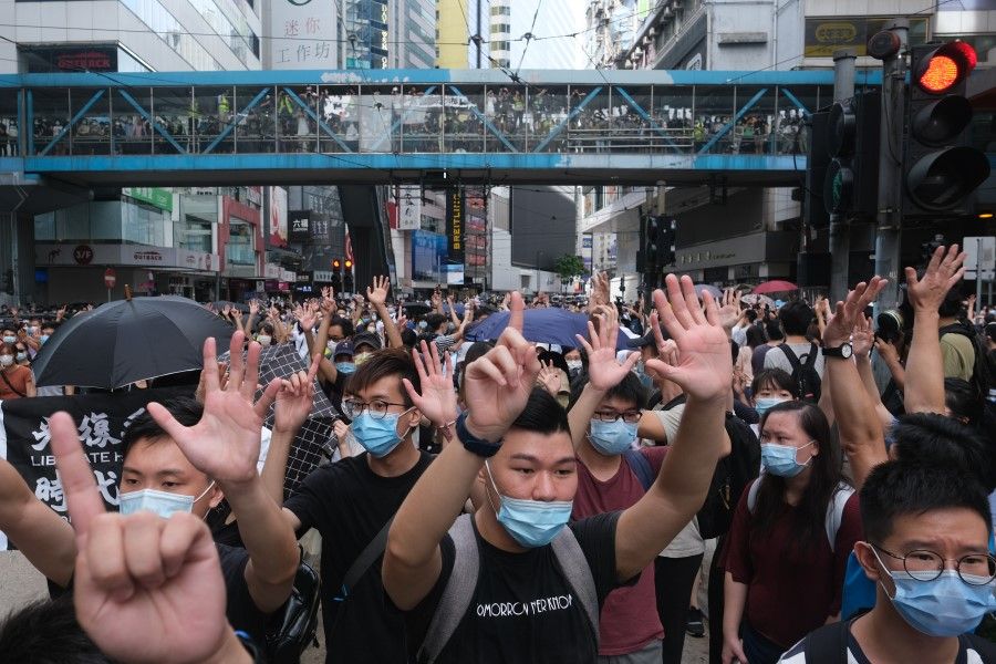 Demonstrators gesture the "Five demands, not one less" protest motto during a protest in Hong Kong, China, on Wednesday, 1 July 2020. Hong Kong woke up to a new reality on Wednesday, after China began enforcing a sweeping security law that could reshape the financial hub's character 23 years after it took control of the former British colony. (Roy Liu/Bloomberg)