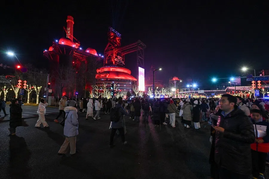 People walk past a former steel mill illuminated on New Year’s eve at the industrial heritage site of Shougang Park in Beijing on 31 December 2024. (Adek Berry/AFP)