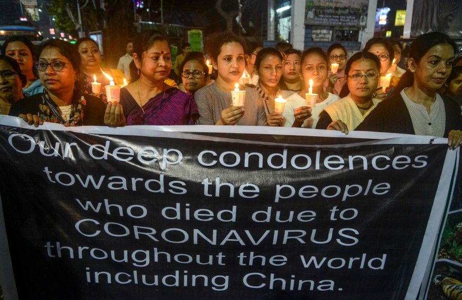 Non-Governmental Organisation (NGO) 'Satarupa' hold a banner and candles to show solidarity with China in the fight against the COVID-19 coronavirus outbreak and to demand the stop of animal killings, during a candle march vigil in Siliguri on February 28, 2020. (Diptendu Dutta/AFP)