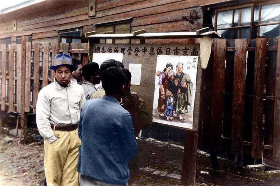 Some Japanese in a concentration facility in Nanjing gaze at a poster on a notice board, criticising the Japanese occupation, September 1945.