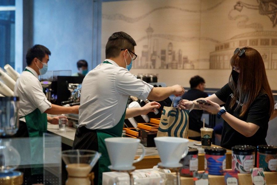 A staff member serves a customer at a Starbucks Coffee house in Beijing, China, 6 July 2020. (Thomas Peter/REUTERS)