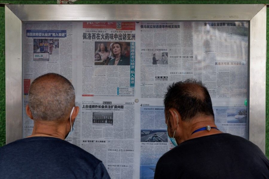 Men read the Global Times newspaper that features a front page article about US House of Representatives Speaker Nancy Pelosi's Asia tour at a street display wall in Beijing, China, 1 August 2022. The front page headline reads: "Pelosi visits Asia in the smell of gunpowder." (Thomas Peter/Reuters)