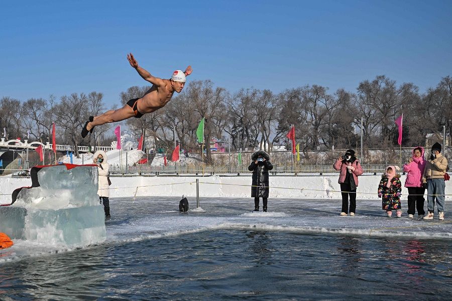 A man dives into a pool cut into the frozen Songhua river in Harbin, Heilongjiang province, China, on 5 January 2023. (Hector Retamal/AFP)